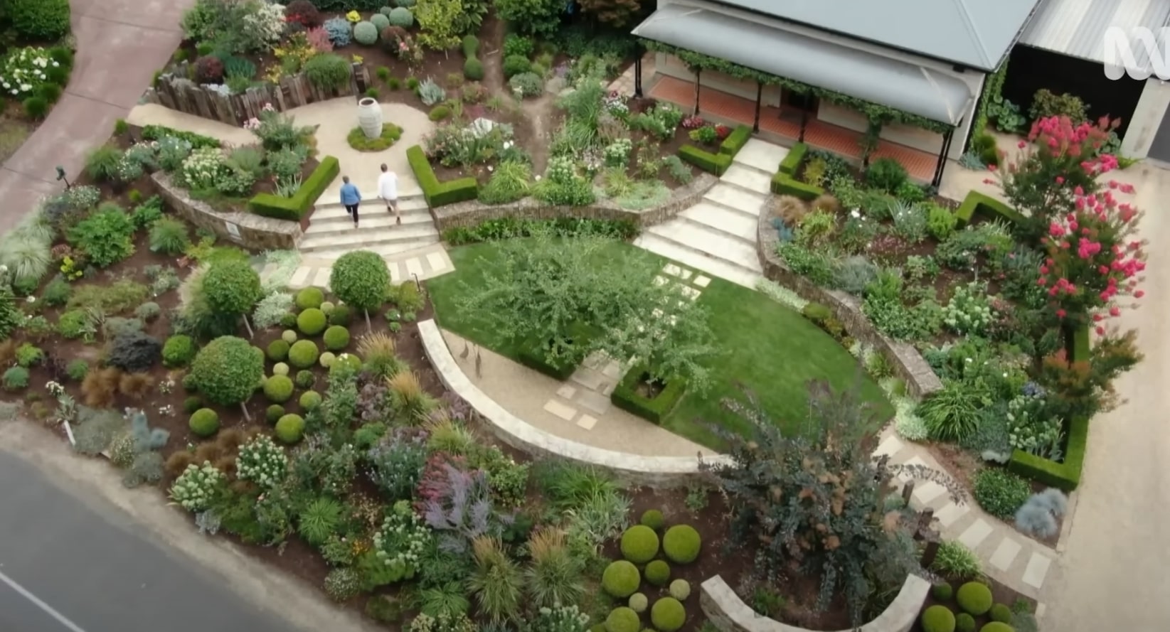 Aerial view of beautifully designed garden with curved pathways, manicured lawns, and diverse plantings