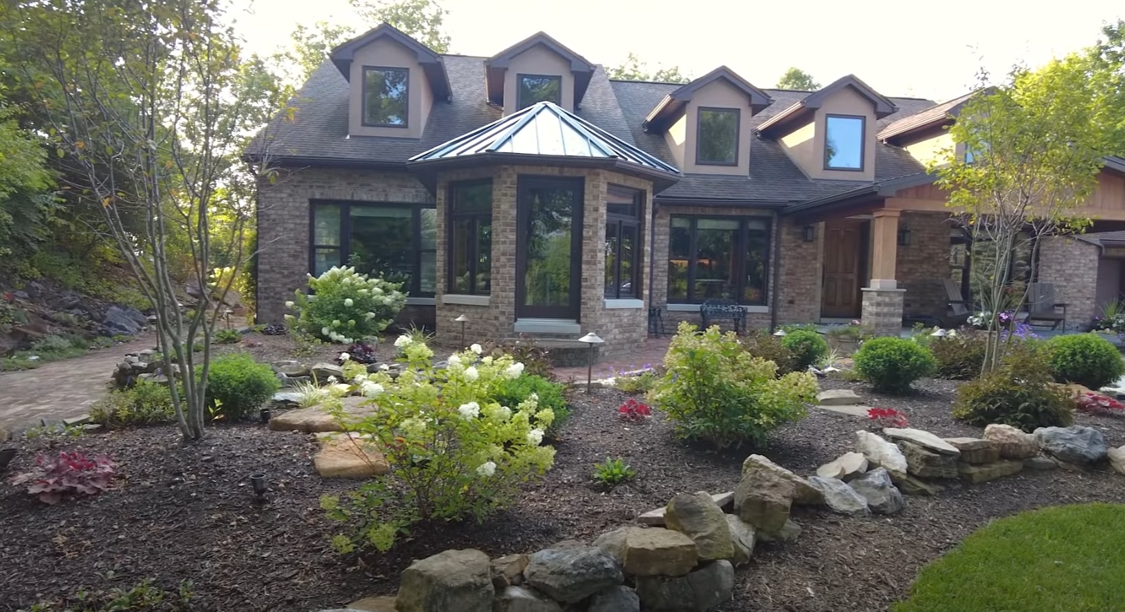 Beautiful landscaped home with professional garden design featuring stone work and lush plantings
